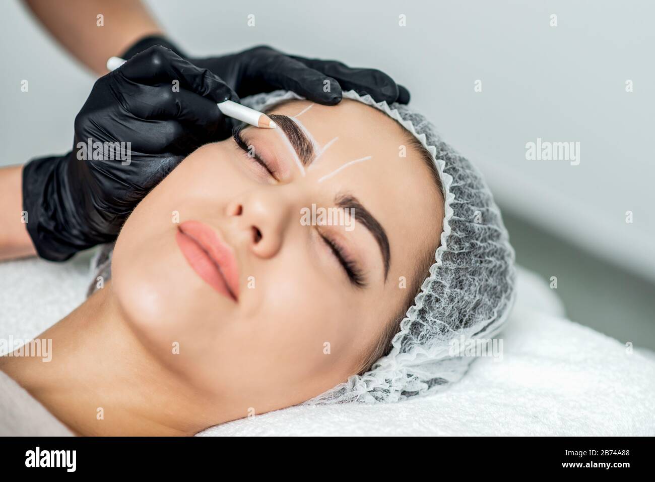 Kosmetikerin tätowieren Augenbrauen ziehen permanent Make-up. Stockfoto