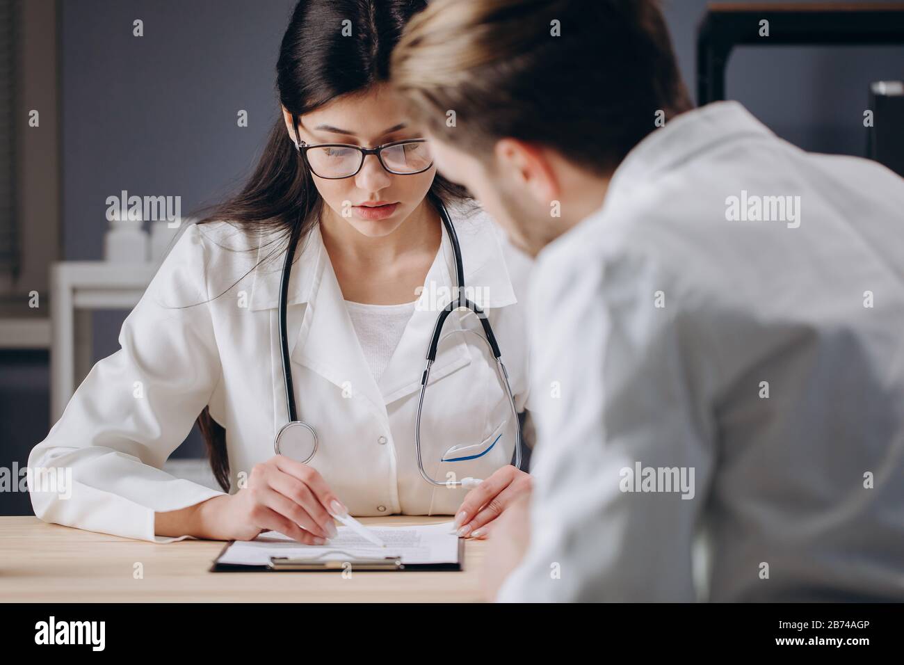 Arzt in einer Brille, der den Behandlungsplan des Patienten erläutert Stockfoto