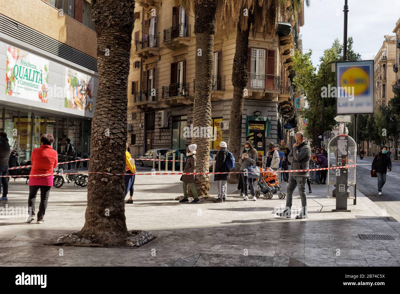 Während der Coronavirus-Pandemie warten die Menschen außerhalb des Supermarktes in Palermo auf Sizilien Stockfoto