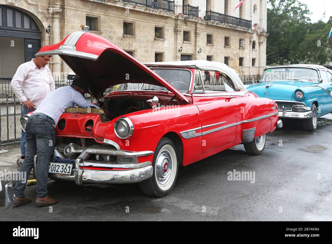 Havanna, Kuba - zwei Männer prüfen den Motor eines roten Oldtimer Stockfoto