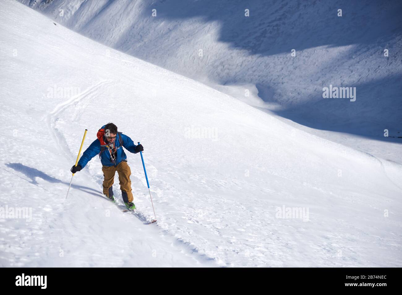 Mann in blauer Jacke Skitouren bergauf Stockfoto