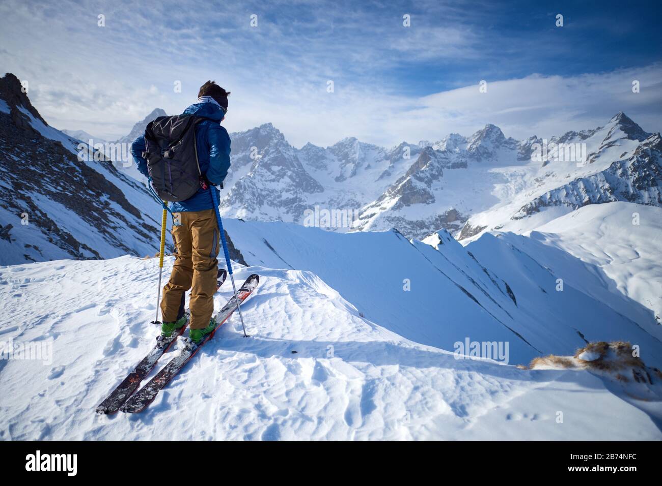 Mann auf Skiern auf dem Bergrücken mit Blick auf die Berge Stockfoto