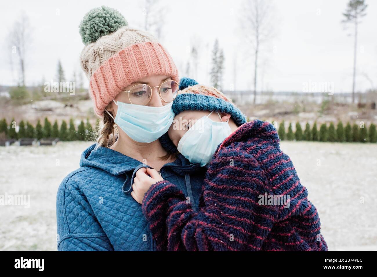 Mutter trägt Sohn mit Gesichtsmasken auf als Schutz vor Virus & Grippe Stockfoto