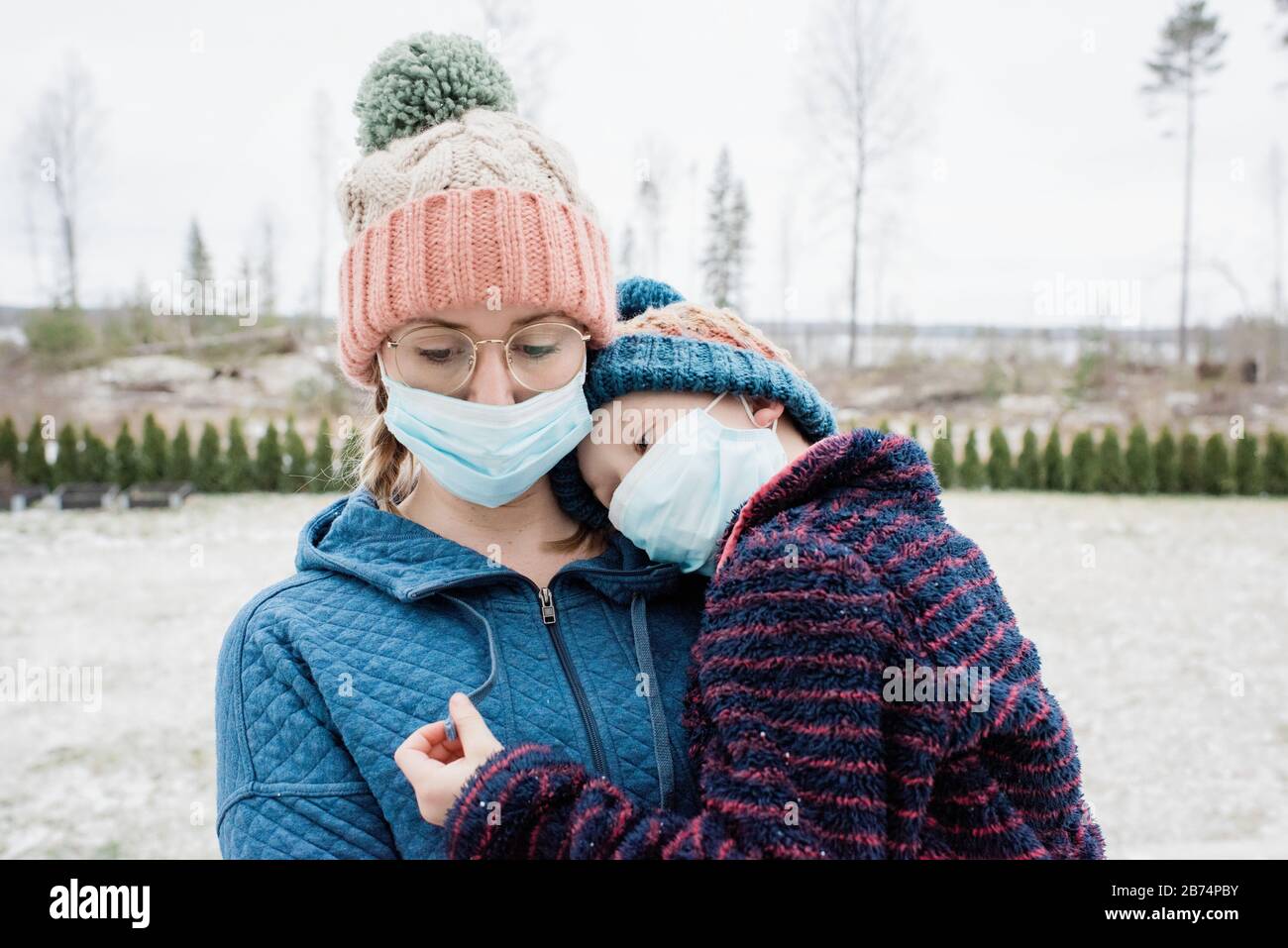 Mutter trägt Sohn mit Gesichtsmasken auf zum Schutz vor Virus & Grippe Stockfoto