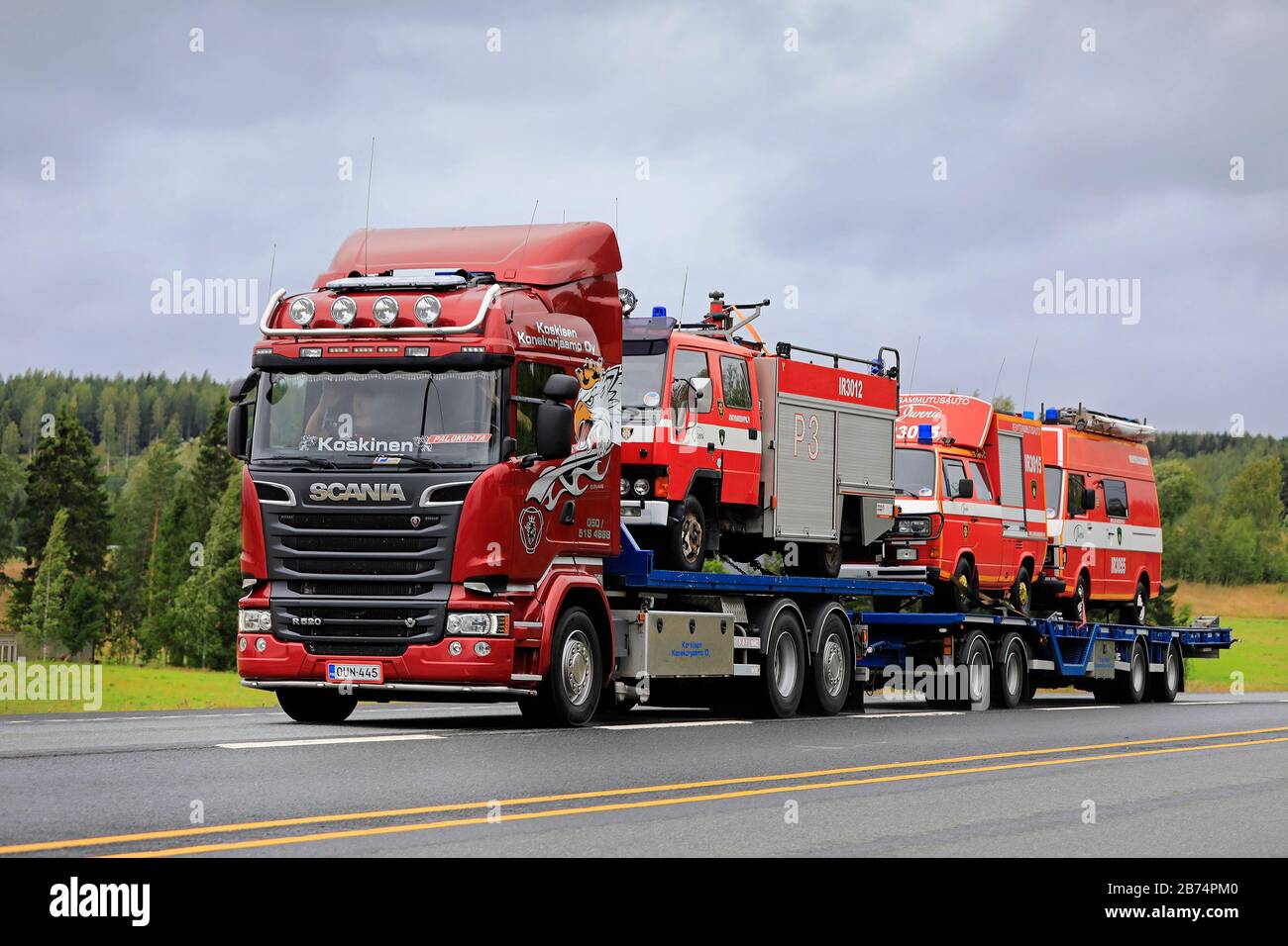 Red Scania R520 Truck Koskisen Konekorjaamo Oy transportiert auf der Autobahn 3 drei alte Feuerwehrfahrzeuge auf Anhänger. Ylöjärvi, Finnland. August 2019. Stockfoto