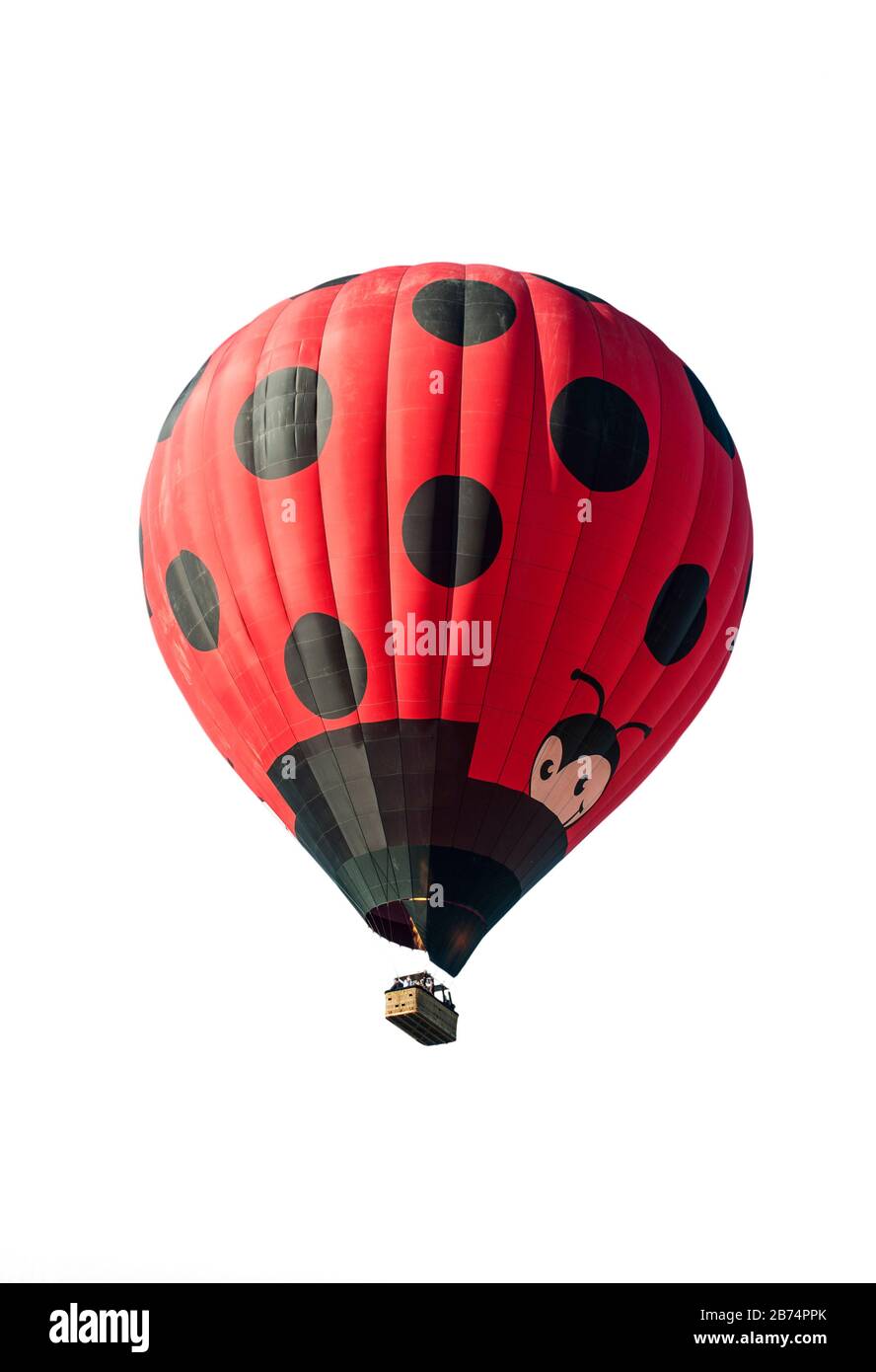 Ballonfahrer/Aeronauten, die im Heißluftballon fliegen und vor weißem Hintergrund einem riesigen roten Marienkäppchen ähneln Stockfoto
