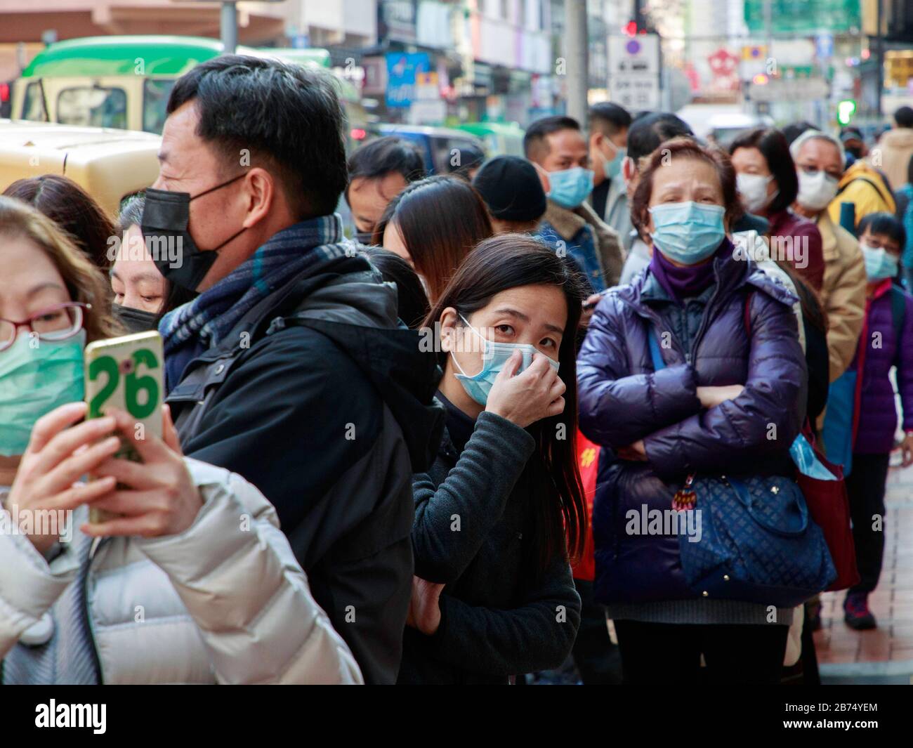 Die Menschen stehen bereit, um kostenlose chirurgische Masken aus einer Apotheke in Hongkong zu bekommen. Jede Person kann 3 Masken erhalten. Stockfoto