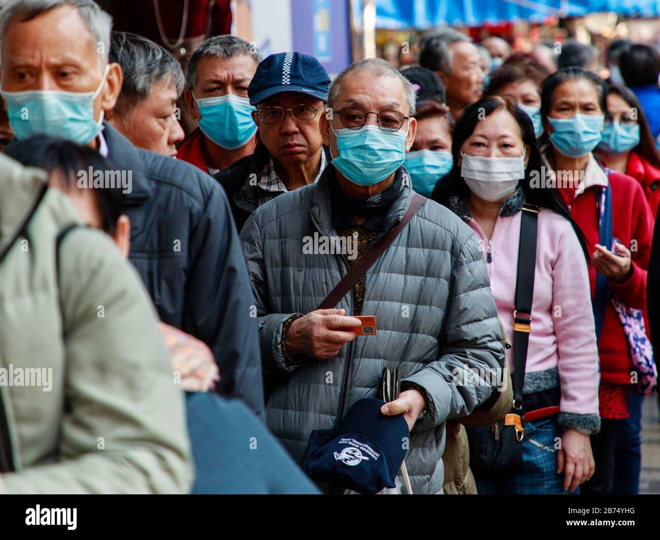 Senioren stellen sich kostenlos maskieren, die von einem Laden verteilt werden. In Hongkong mangelt es in der Stadt an chirurgischer Maske. Stockfoto
