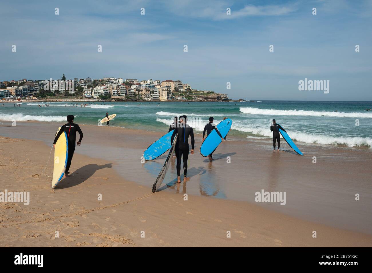 27.09.2019, Sydney, New South Wales, Australien - junge Männer in Wetsuits tragen ihre Surfbretter in Richtung Meer, während sie einen Surfkurs am Bondi Beach nehmen. [Automatisierte Übersetzung] Stockfoto