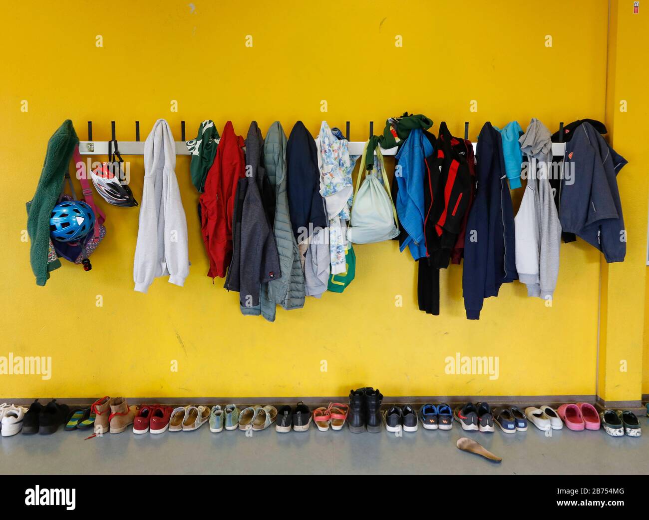 Jacken und Taschen hängen an einer Garderobe in einer Berliner Grundschule, Schuhe sind auf dem Boden. [Automatisierte Übersetzung] Stockfotografie