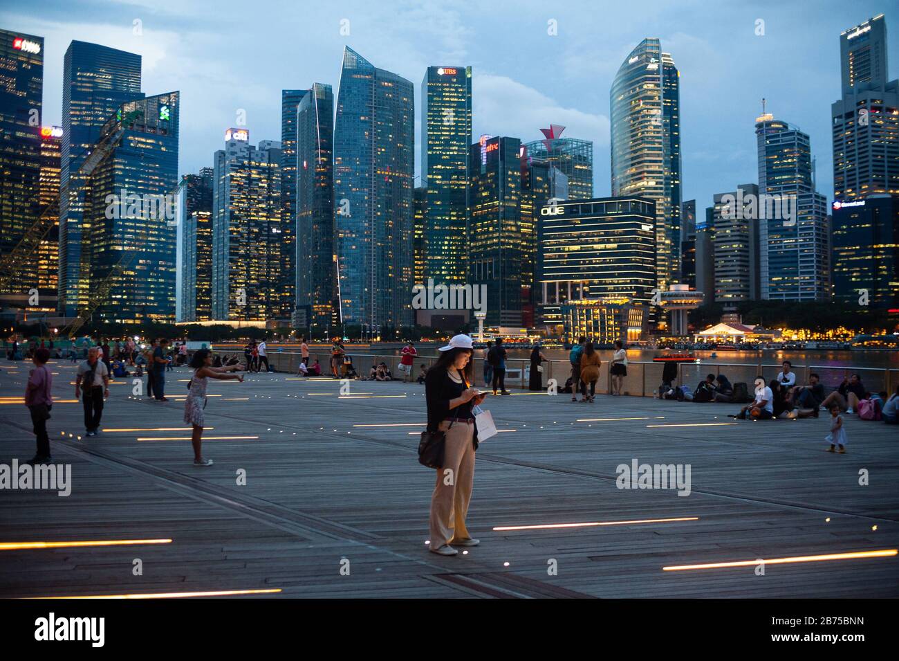 14.12.2018, Singapur, Republik Singapur, Asien - Menschen am Ufer des Singapur-Flusses in der Marina Bay mit der abendlichen Skyline des Geschäftsviertels im Hintergrund. [Automatisierte Übersetzung] Stockfoto