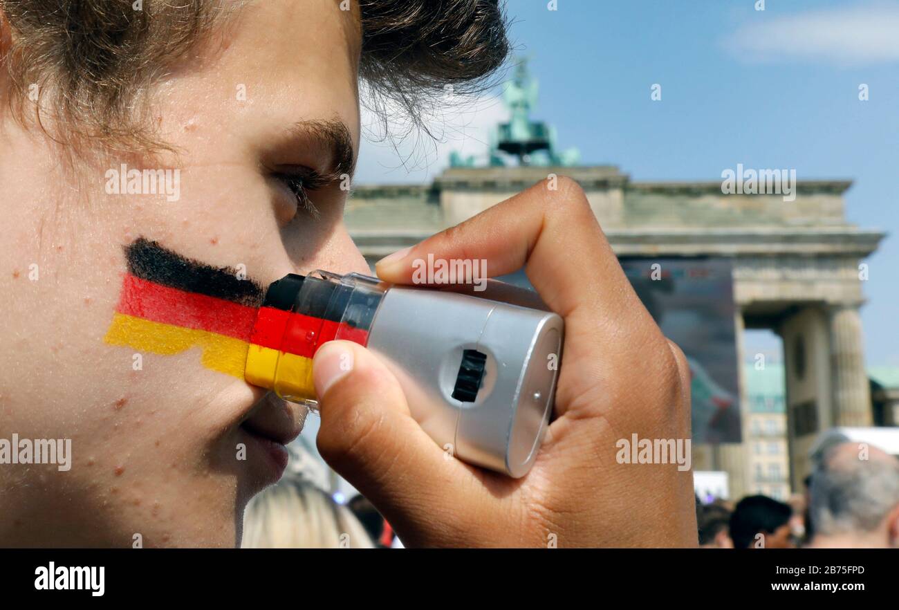 Ein deutscher Fußballfan wird am 17. Juni 2018 auf seiner Wange am Brandenburger Tor in der Berliner Fanmeile für das Eröffnungsspiel Deutschland gegen Mexiko eine Deutschlandfahne anstreichen lassen. [Automatisierte Übersetzung] Stockfoto