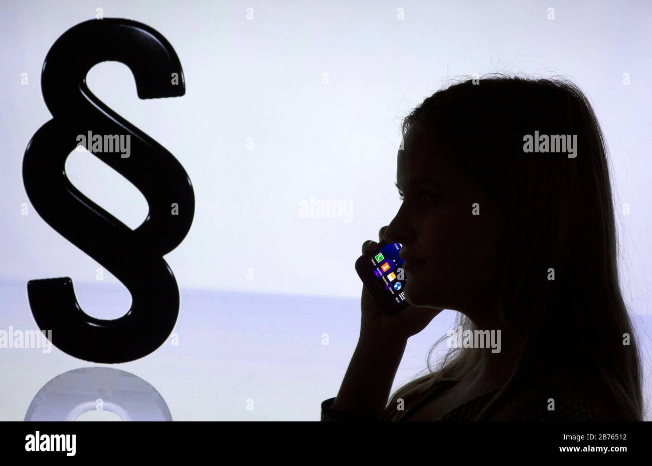 Die Silhouette einer Frau mit einem Smartphone in der Hand ist vor dem Logo von "Paragraphen" am 12.01.2016 zu sehen. Telefonische Beratung in Rechtsfragen. [Automatisierte Übersetzung] Stockfoto