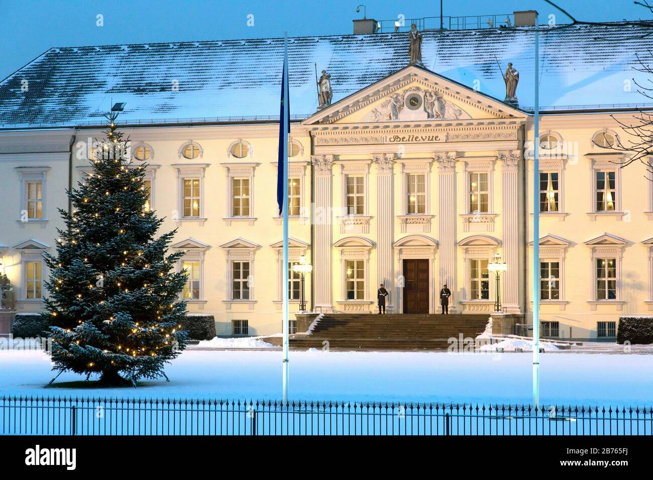 Ein dekorierter und beleuchteter Weihnachtsbaum wird am 06.01.16 im schneebedeckten Schloss Bellevue, dem Sitz des Bundespräsidenten, aufgestellt. Am Eingang zum Schloss Bellevue stehen zwei Soldaten des Schützenbataillons der Bundeswehr. [Automatisierte Übersetzung] Stockfoto