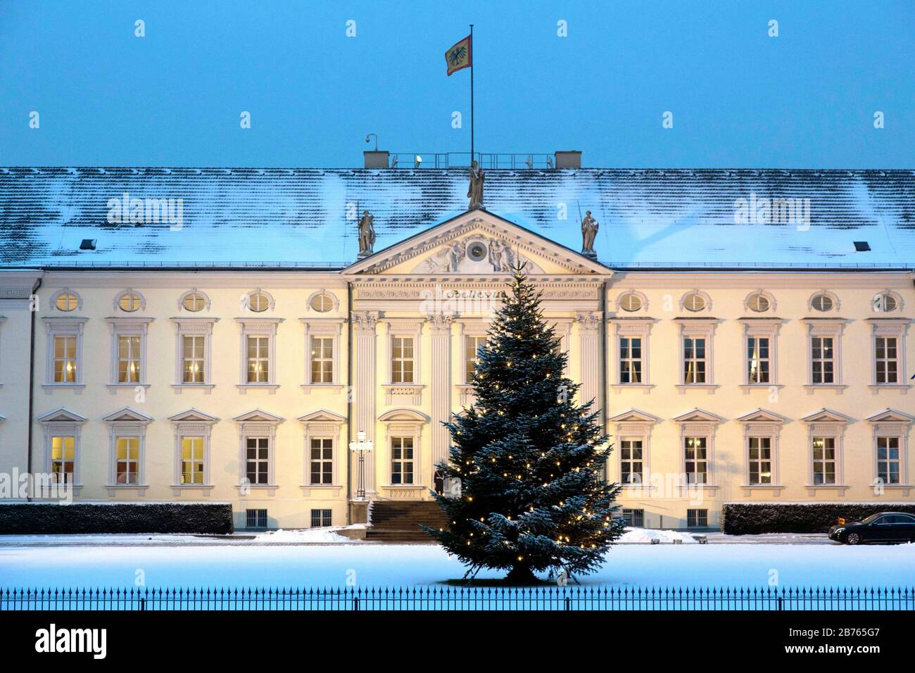 Ein dekorierter und beleuchteter Weihnachtsbaum wird am 06.01.16 im schneebedeckten Schloss Bellevue, dem Sitz des Bundespräsidenten, aufgestellt. Am Eingang zum Schloss Bellevue stehen zwei Soldaten des Schützenbataillons der Bundeswehr. [Automatisierte Übersetzung] Stockfoto