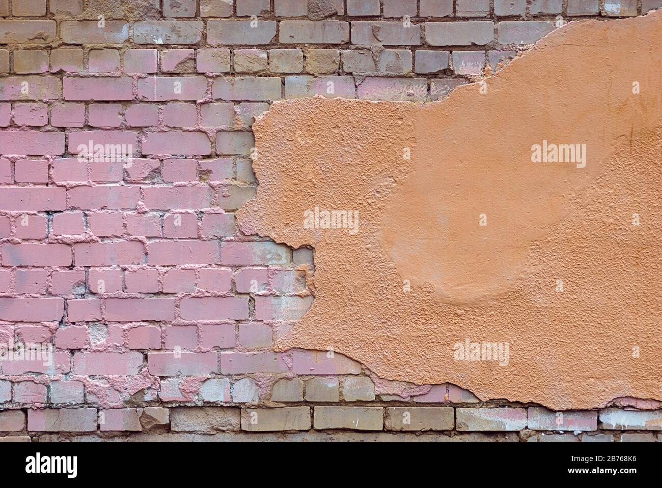 Alte beschädigte Ziegelwand mit Stuck- und Farbflecken Stockfoto
