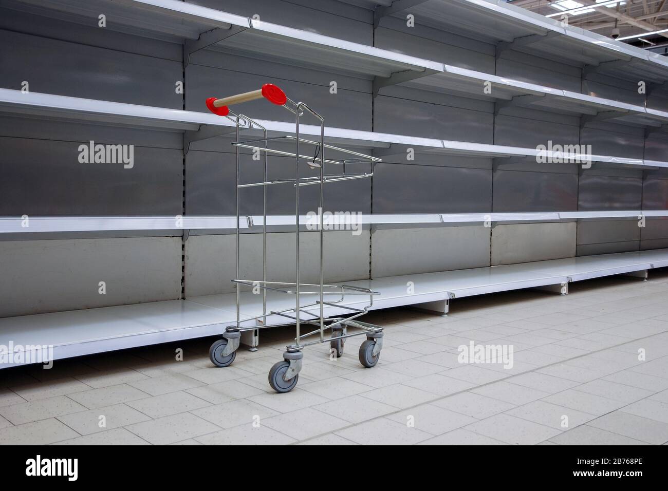 Leere Regale und Einkaufswagen im Supermarkt, alle ausverkauft wegen Panik durch Virusausbruch Stockfoto