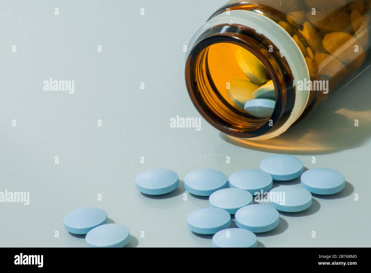 Verschüttete blaue medizinische Pillen über die graue Oberfläche, kleine Tabletten helfen für die Gesundheit Stockfoto