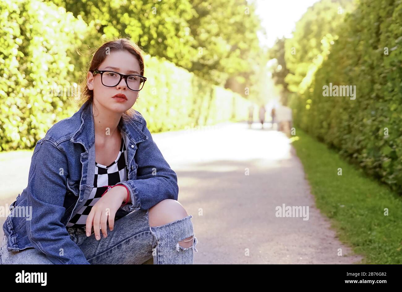 Ein junges Mädchen mit Brille in einem Park auf einer grünen Gasse Stockfoto