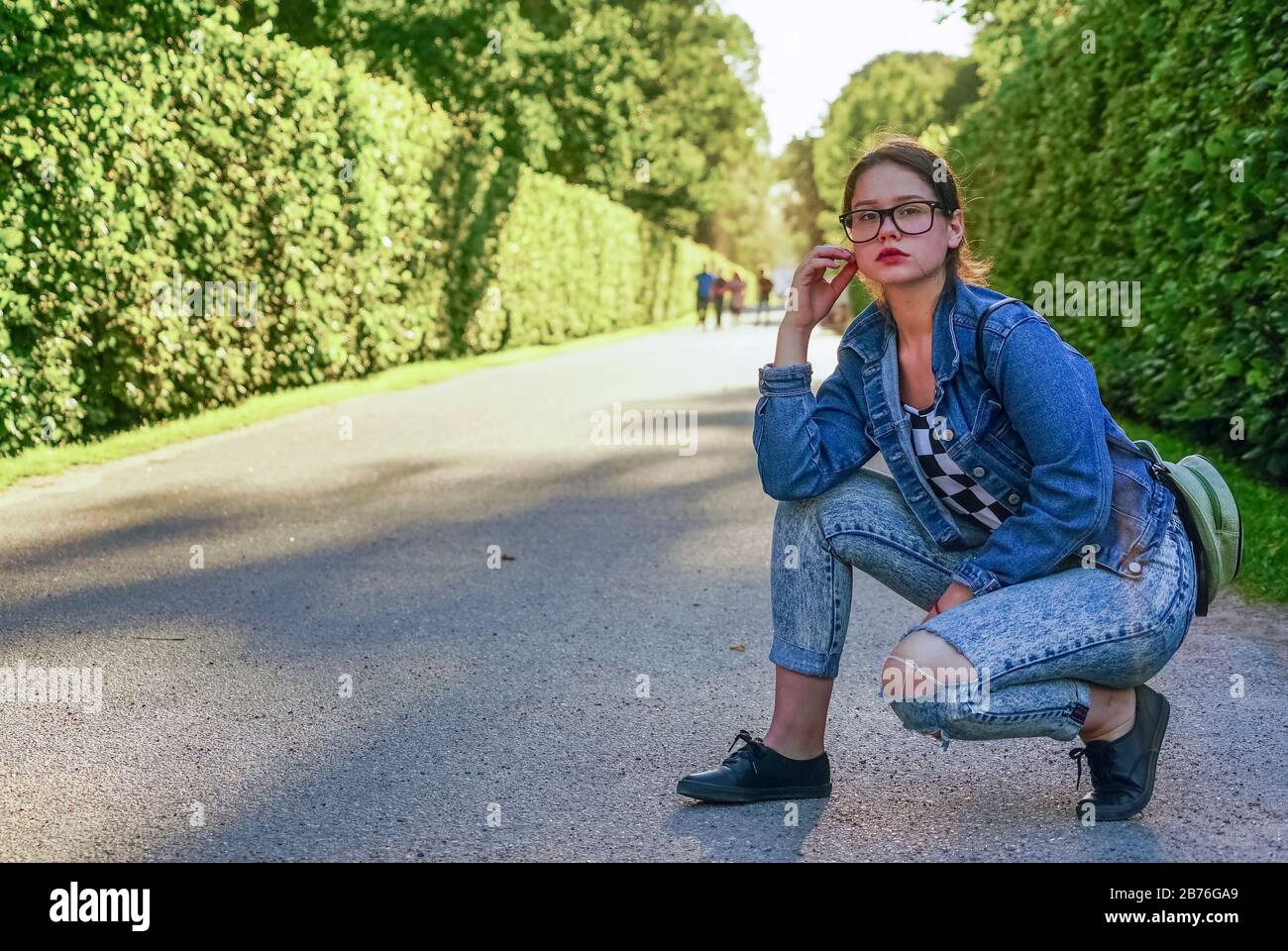 Ein junges Mädchen mit Brille in einem Park auf einer grünen Gasse Stockfoto