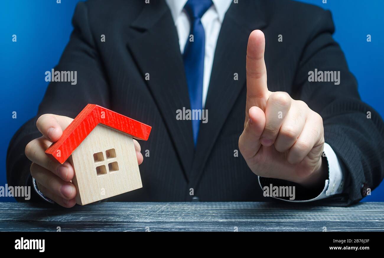 Der Mann mit einem Haus macht eine Geste der Aufmerksamkeit. Rechtsberatung zu Vertragsbedingungen Vertragsabschluss für den Kauf von Immobilien, Darlehen und Hypothekenkrediten. Warnung, Stockfoto