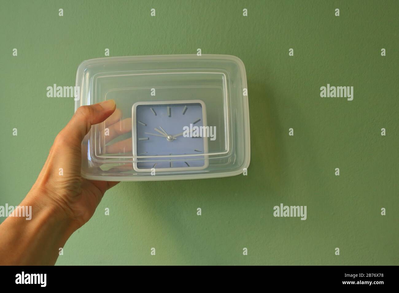 Halten Sie eine geschlossene Kunststoffbox mit analoger Uhr darin. Zeitsparend, haben Sie eine gute Zeitkonzept-Metapher Stockfoto