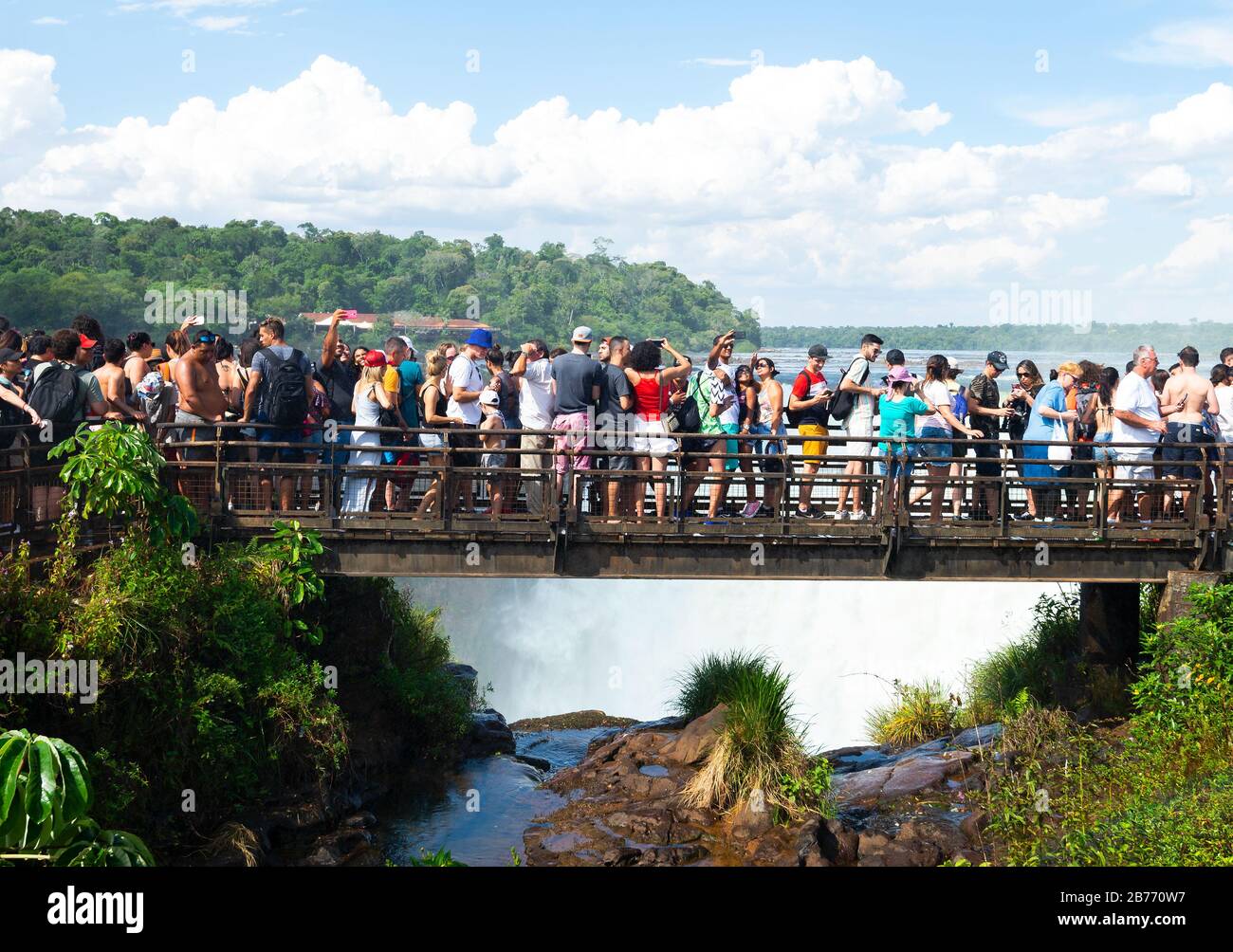 Über den Tourismus an den Iguassu Wasserfällen, Puerto Iguazu, Argentinien wegen der Feiertage. Zahllose Touristen in einer Fußgängerbrücke, die auf die Teufelskehle blickt, fallen. Stockfoto