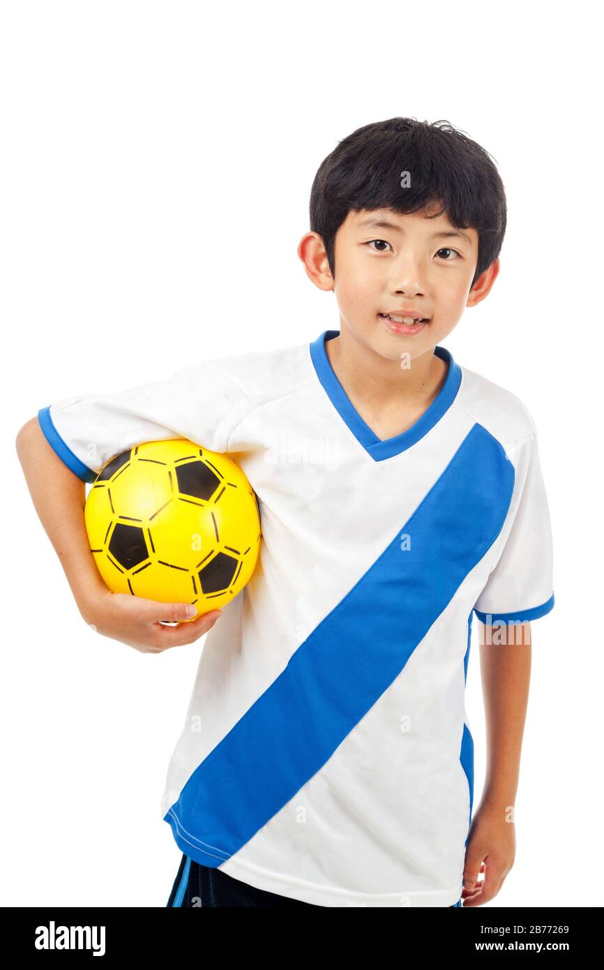 Heiterer junger asiatischer Junge hält Fußball isoliert auf weißem Hintergrund. Stockfoto
