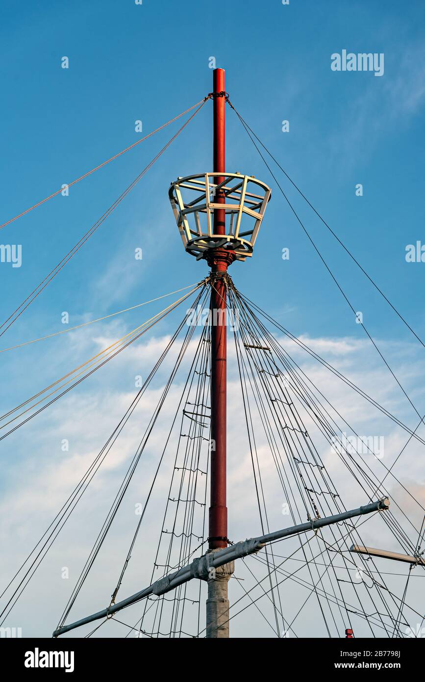 Mast eines Schiffes mit seinen Seilen, seinem Schwanz für die Uhr und einem schönen bewölkten Himmel dahinter Stockfoto