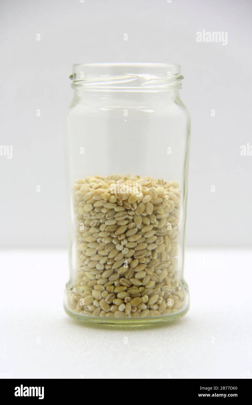 Glasbecher mit Gerste auf weißem Hintergrund, Seitenansicht. Das Konzept der gesunden Ernährung, Ernährung, vegetarische Produkte. Stock-Foto mit leerem Platz für Text und Design. Stockfoto