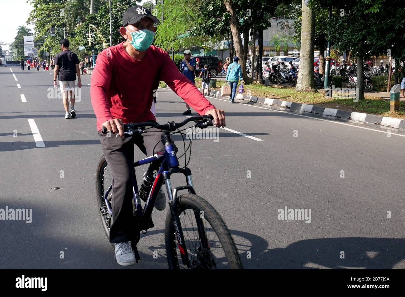 Ein Mann trägt eine Grippemaske, während er mit seinem Fahrrad auf einem Auto Free Day Event mitfährt. Stockfoto