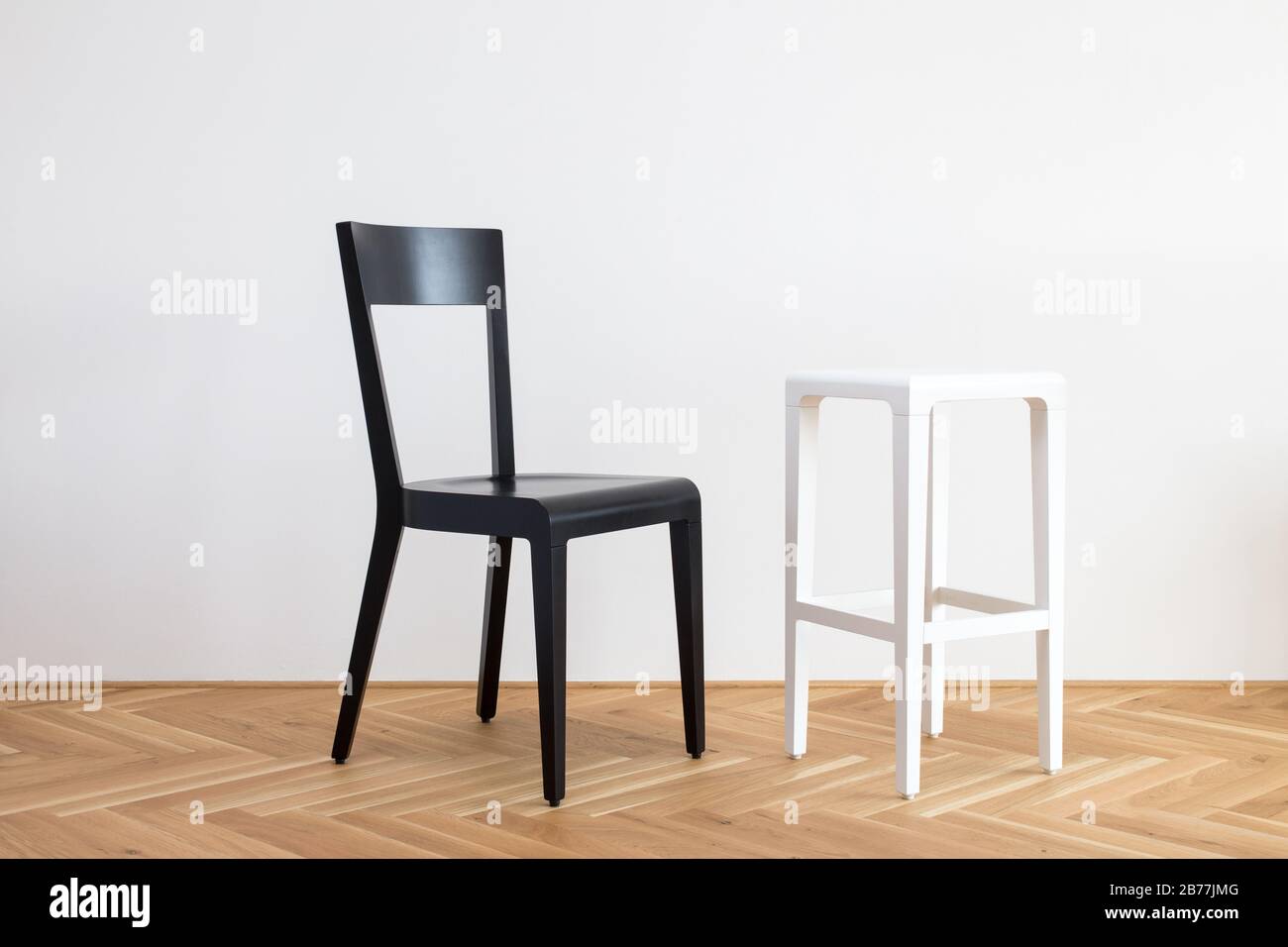 Moderner, vereinfachter, schwarz-weißer Stuhl auf einem Holzflor vor weißem Hintergrund Stockfoto