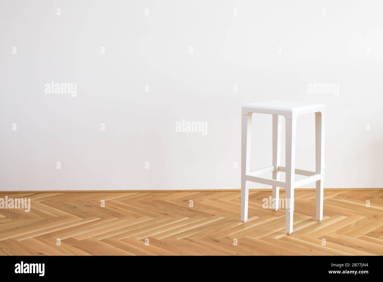 Moderner, vereinfachter weißer Stuhl auf einem Holzflor vor weißem Hintergrund Stockfoto