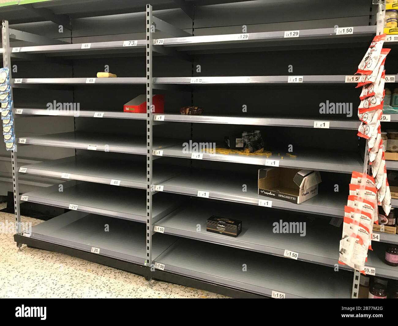 Leere Regale im Supermarkt in England. Käufe aufgrund von Coronavirus Panik in britischen Geschäften werden mit leeren Regalen gelassen. Stockfoto