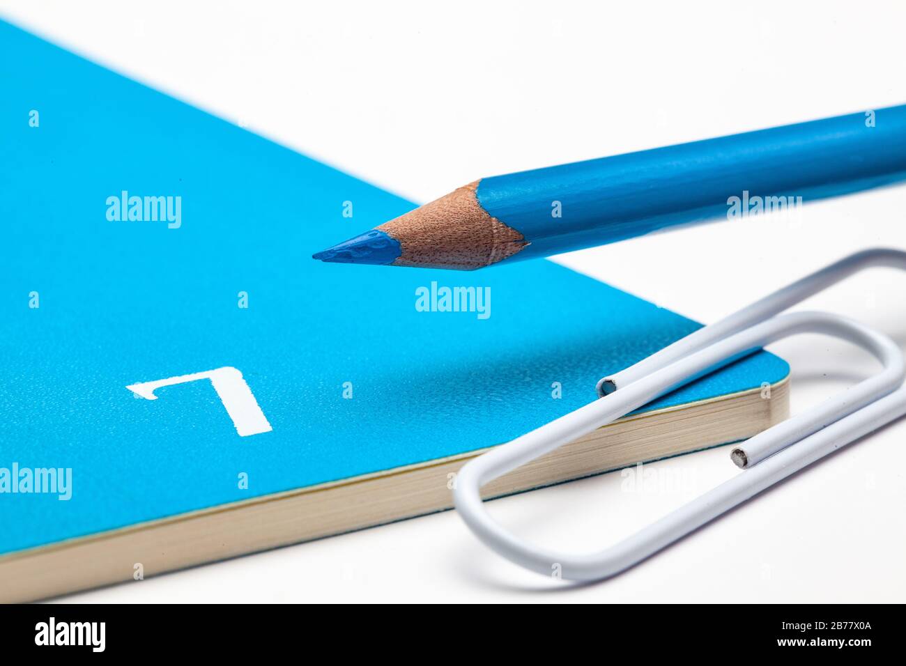 Veranstalter für den Monat Juli, blauer Bleistift und weißer Büroklammer auf dem weißen Tisch. Stockfoto