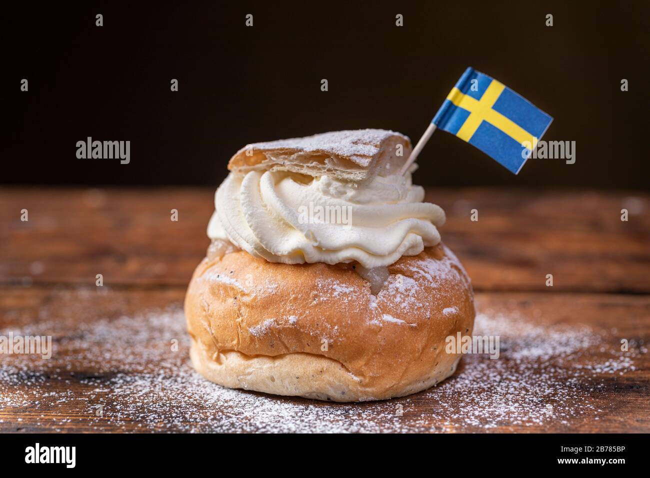 Semla, fastelavnsbolle, fastlagsbulle. Ein traditionelles skandinavisches Kardamom-Bun mit Mandelpaste. Mit schwedischer Flagge dekoriert. Auf einem Woo Stockfoto