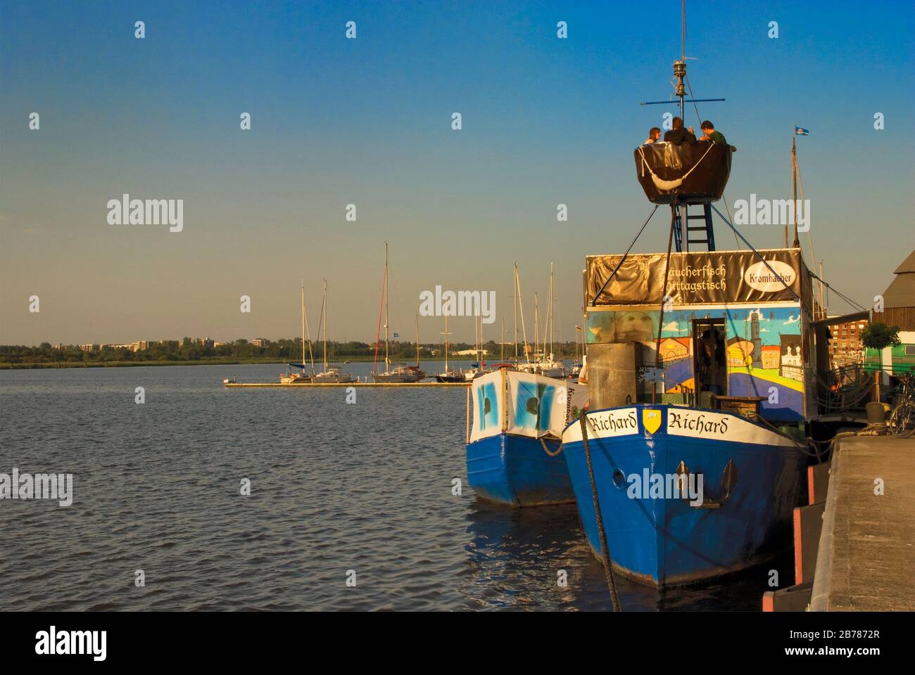Am Ufer des Flusses Warnow in Rostock, Mecklenburg-Vorpommern, Deutschland, nisten in Krähen Menschen auf dem Boot Stockfoto