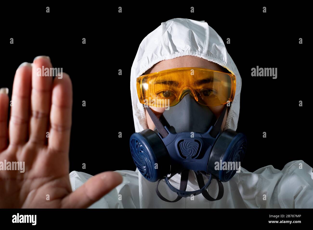 Hand up STOP seufzt Frau in einer chemischen Schutzkleidung und Gasmaske mit Brille am weißen Hintergrund, Frauen Wissenschaftler im Sicherheitsanzug, Safety VI Stockfoto