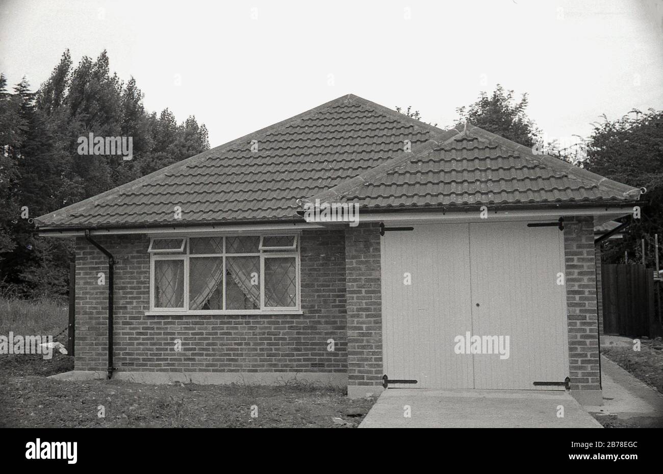 Ende der 60er, vielleicht Anfang der 70er Jahre neues einstöckiges Haus aus Backstein mit dem Titel Dach, ein kürzlich errichteter, mit integrierter Einzel-Garage, England, Großbritannien. Stockfoto