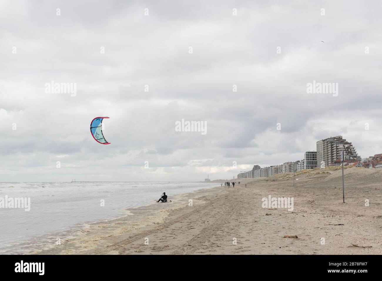 Oostduinkerke, Belgien - 26. Februar 2020: Kitesurfer, die an einem kalten und windigen Tag am Strand ruhen Stockfoto
