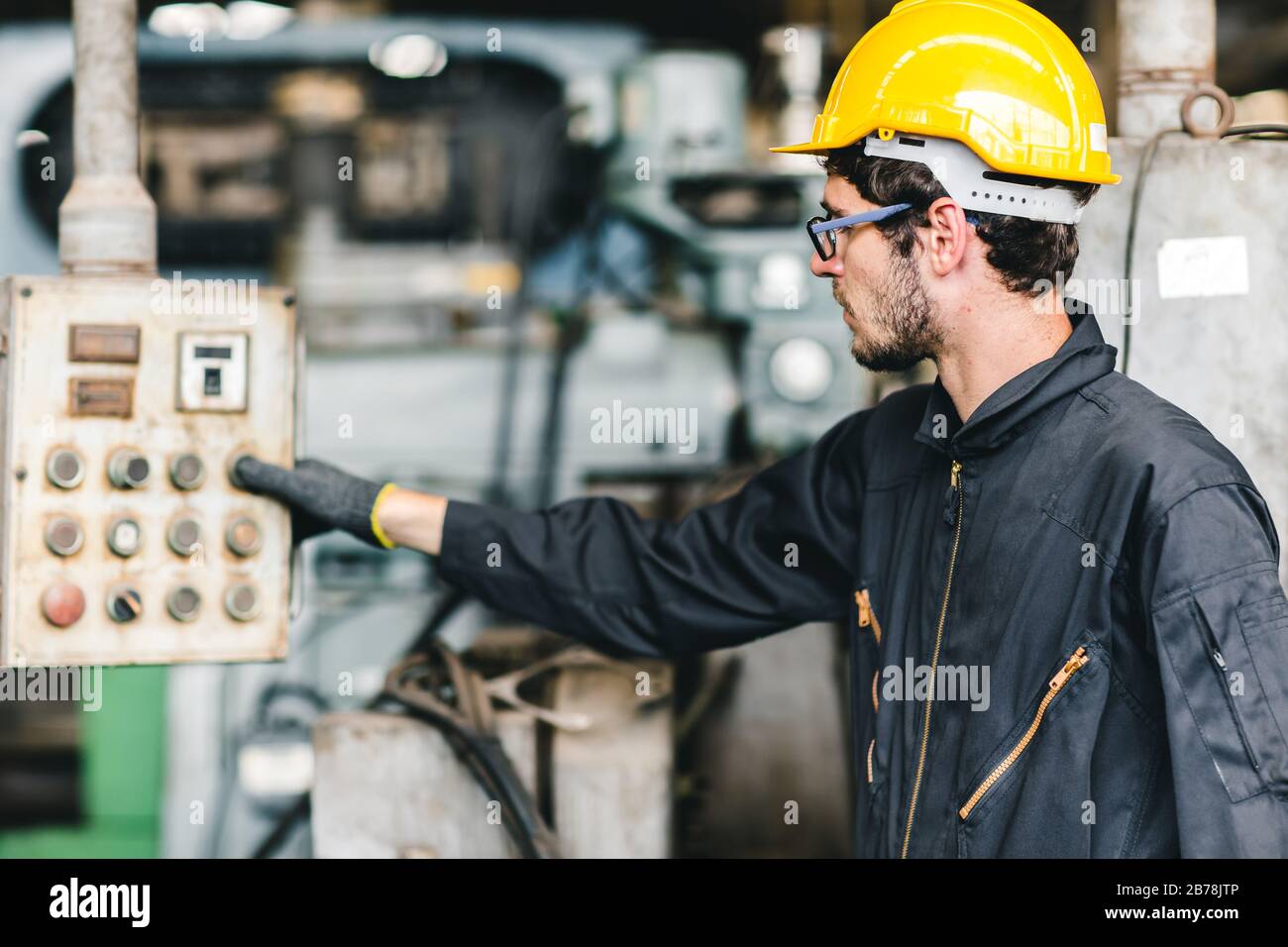 Junge amerikanische Arbeiter beabsichtigen, in einer schweren Industriefabrik zu arbeiten.Steuern Sie die Maschine durch Drücken der Taste. Stockfoto