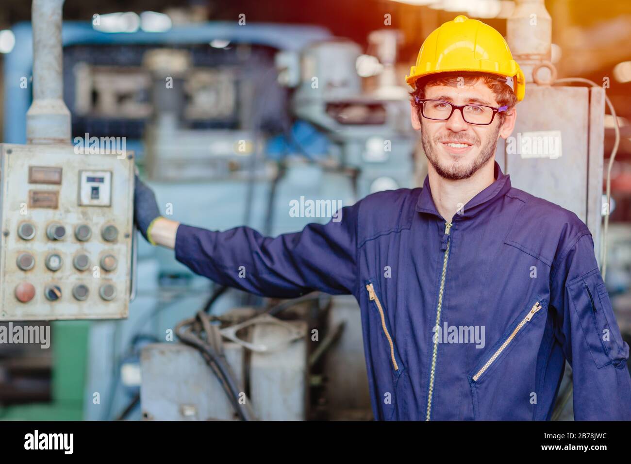 Fröhlicher amerikanischer Teenager.Techniker lächelt für die Wartung der Reparaturmaschine in schwerer Undulheit mit Saftanzug und Helm. Stockfoto