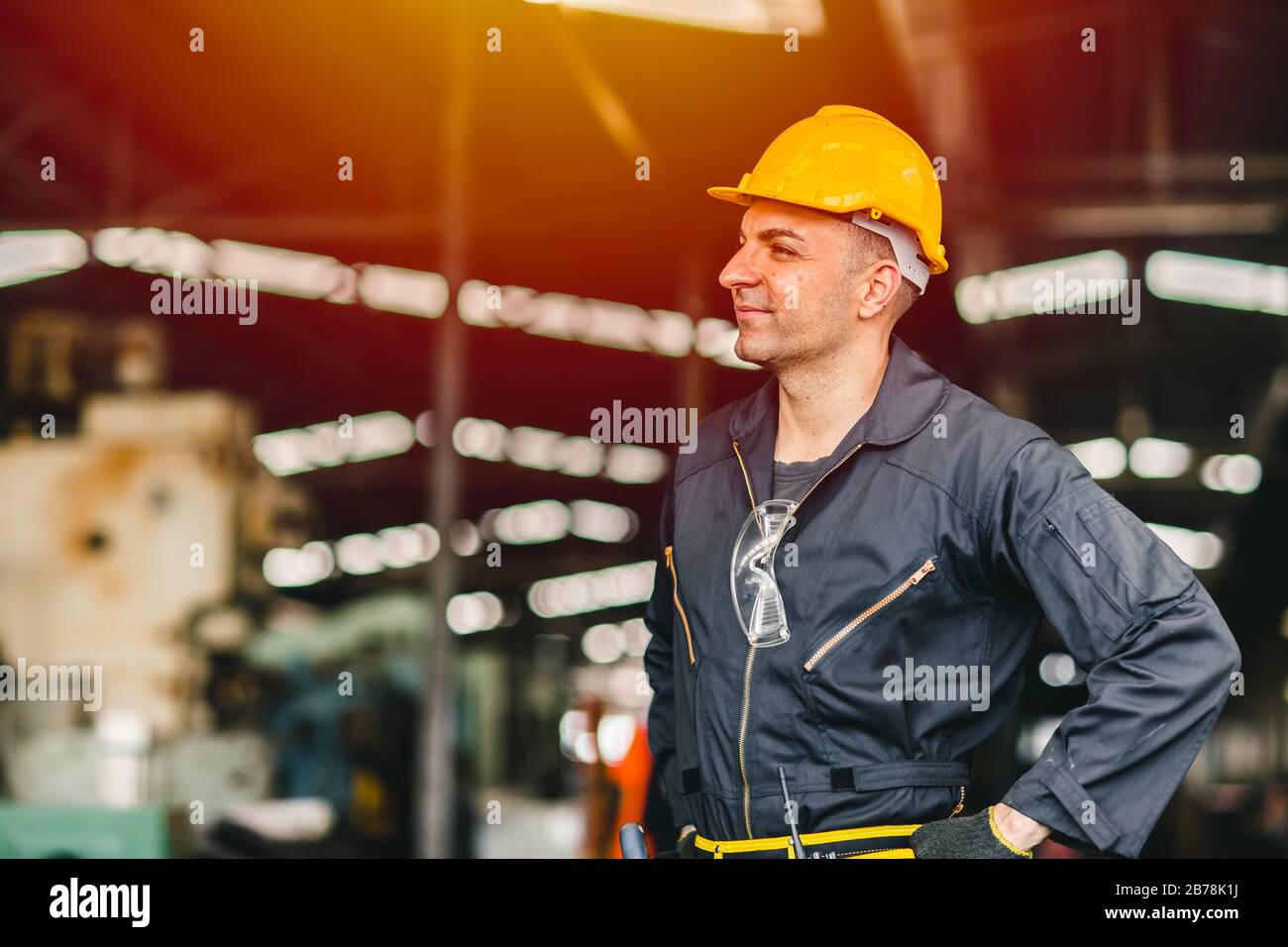 Fröhlicher Arbeiter, Portrait lächelt gutaussehend Arbeit mit Sicherheitsanzug Werkzeuge Gürtel und Funkdienst Mann in der Fabrik. Stockfoto