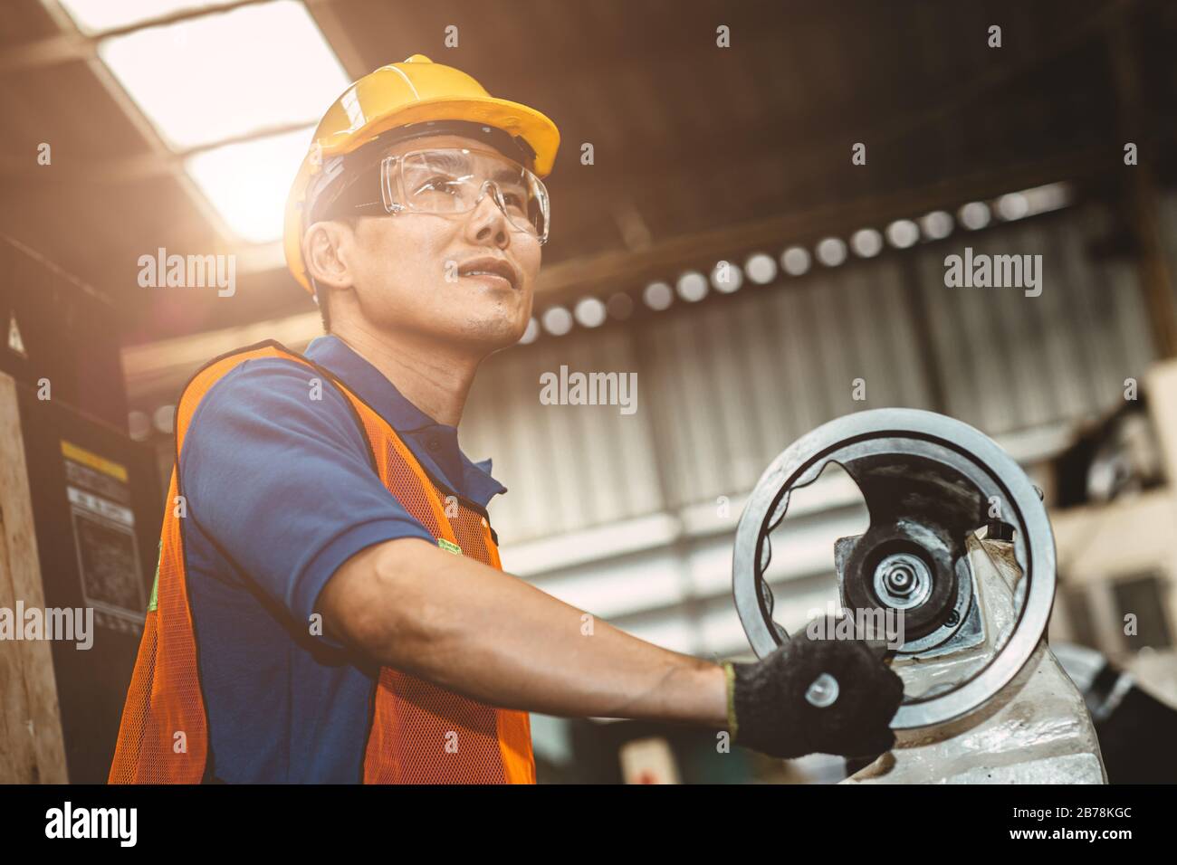 Asian Woker ist stolz auf seine Arbeit in der Schwerindustrie im Produktionslinienprozess und lächelt in der Fabrik glücklich. Stockfoto