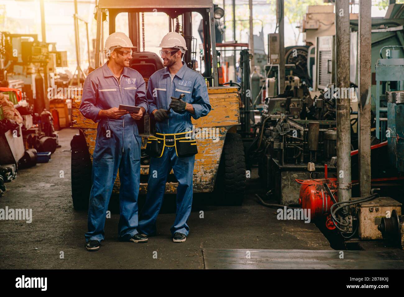 Glücklicher Arbeiter, der in der Schwerindustrie arbeitet und lächelnd miteinander spricht. Stockfoto