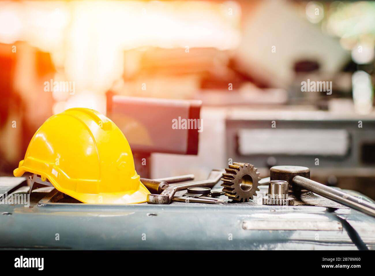 Gelbe Helm-Hardhut mit Instrument-Werkzeugmaschinen im Werk für den Hintergrund. Stockfoto