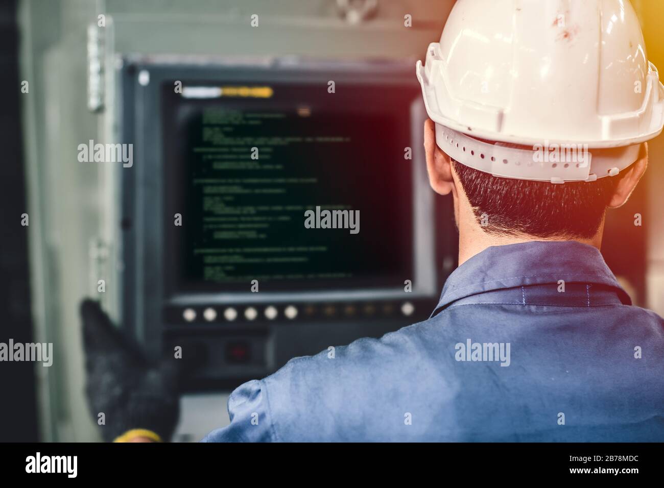 Arbeiter bedienen CNC-Maschine mit G-Code-Monitor, hochqualifizierte Arbeitsbranche mit Sicherheitskleidung. Stockfoto