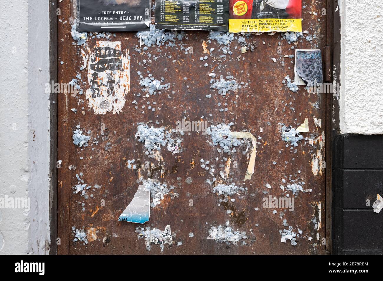 Blu Tack Kleber auf der alten Tür verwendet von Fly Plakaten in Glasgow, Schottland, Großbritannien Stockfoto