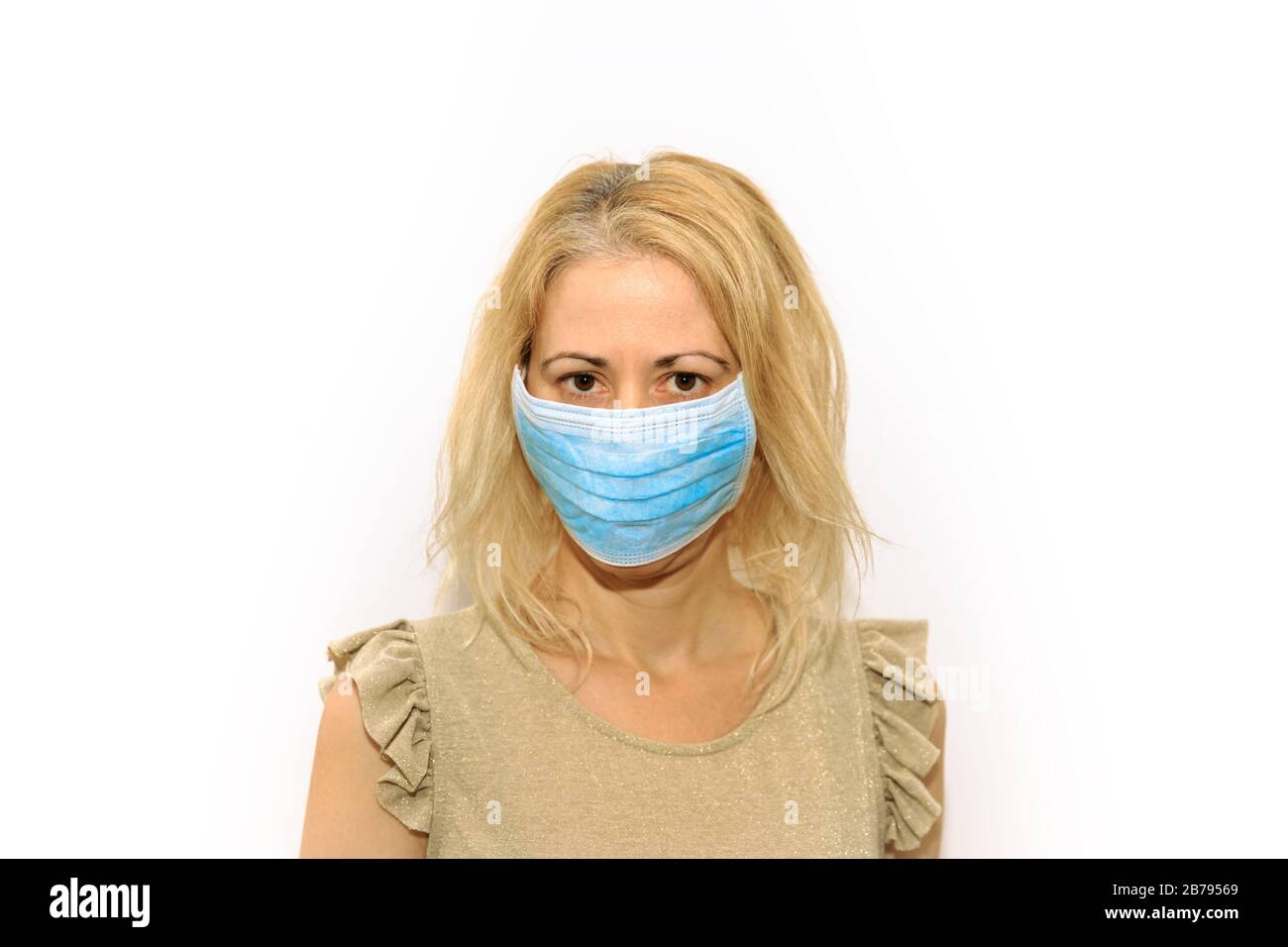 Vorderansicht eines blonden Mädchens mit einer sanitären Maske auf weißem Hintergrund isoliert. Konzept des epidemischen Ausbruchs, Quarantäne für die öffentliche Gesundheitsversorgung und Stockfoto