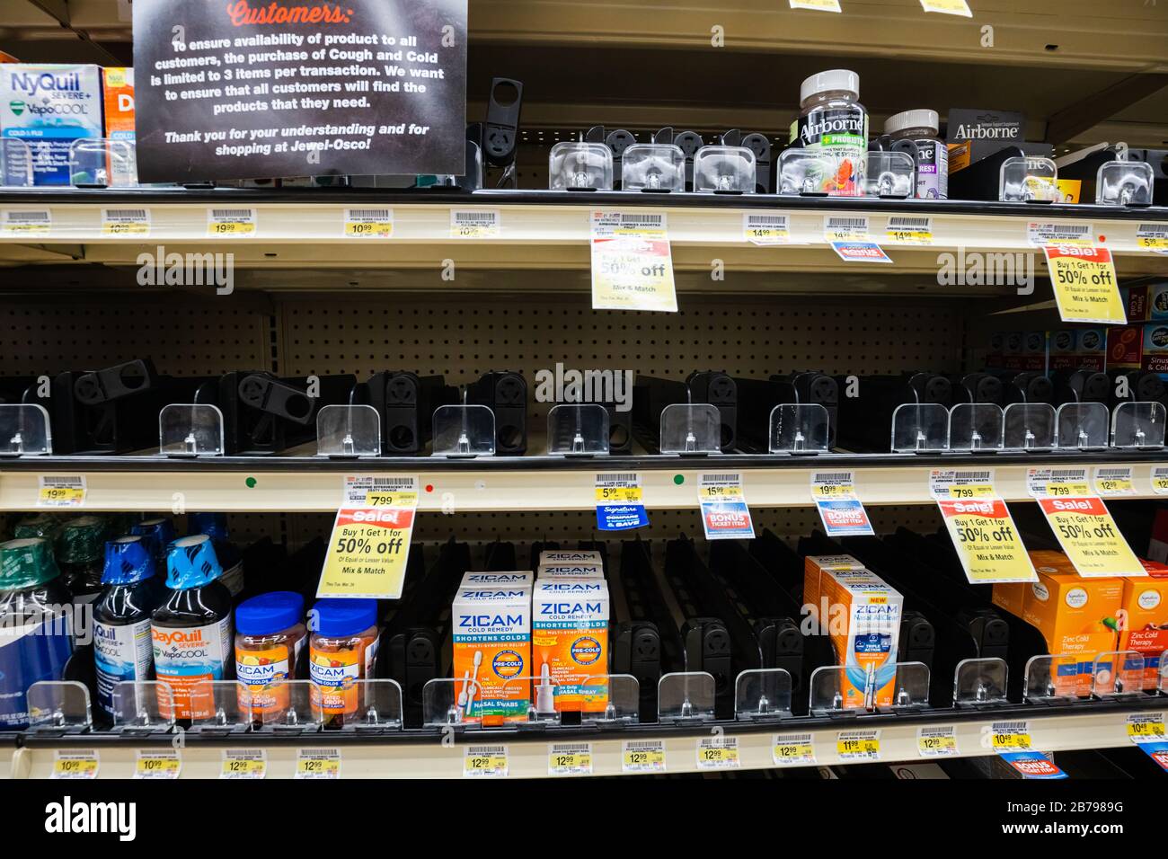 Fast leere Regale mit über dem Ladentisch befindlichen Medikamenten in einem Supermarkt, da Coronavirus für Käufer Panik verursacht Stockfoto